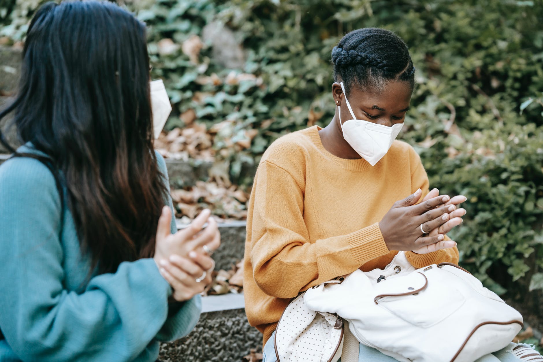 multiethnic women in masks wiping hands in park