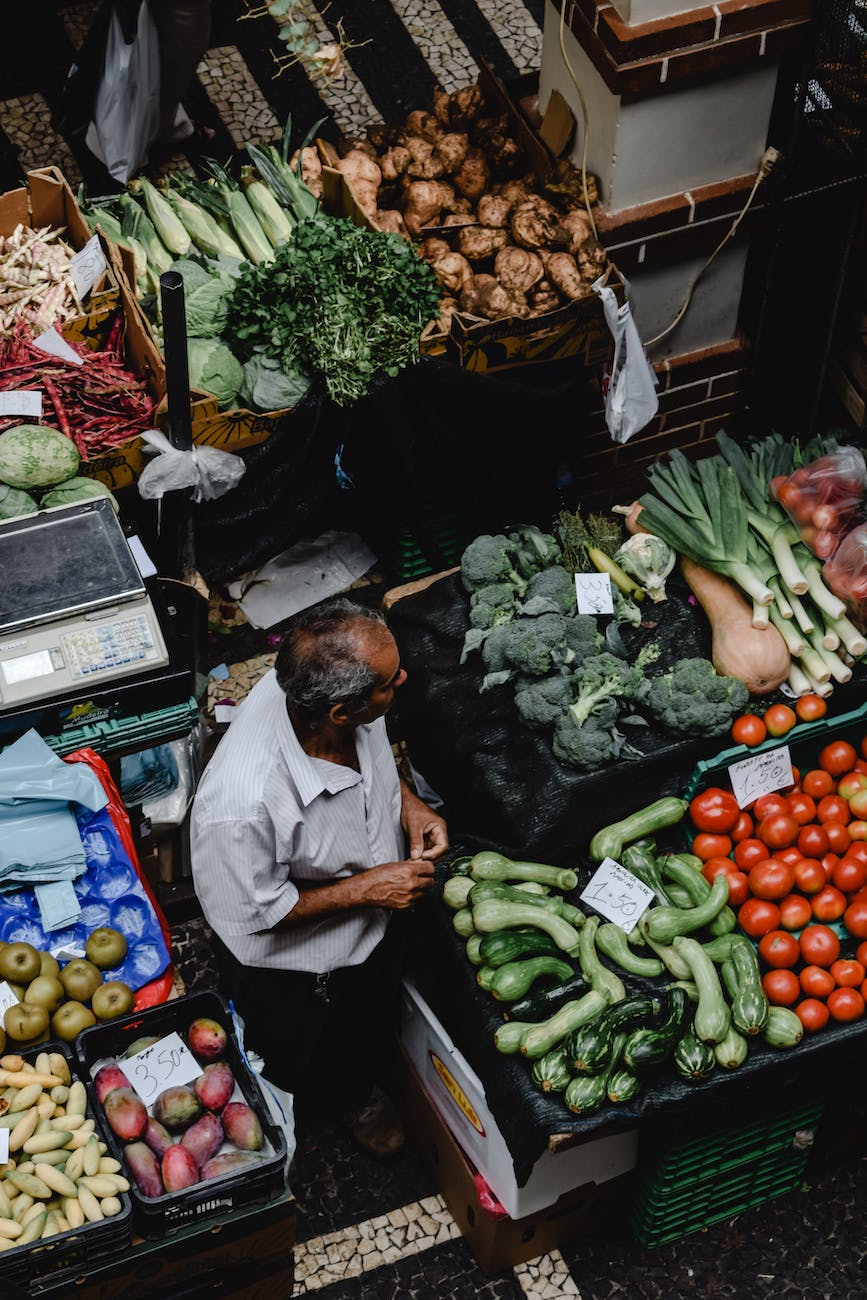 high angle shot of a man looking at vegetables on a market